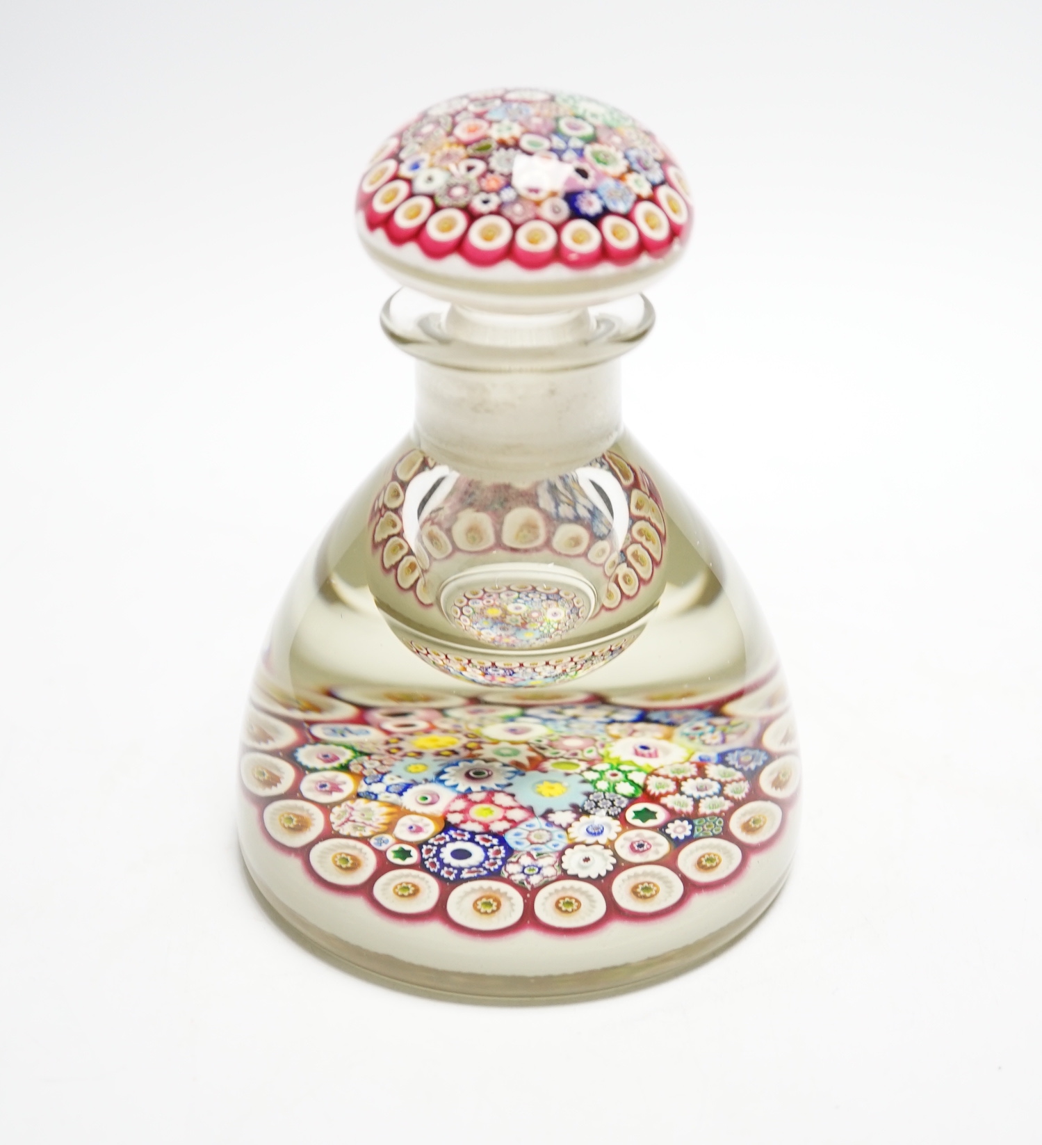 A Paul Ysart close packed millefiori glass inkwell or bottle and stopper, Caithness period, scratched signature ’P. Ysart’ to underside, opaque white ground, 10cm diameter, 13.5cm high